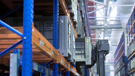 Working in factory warehouse. Scene. Technology for placing containers on shelves in warehouse of...