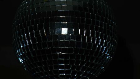 Close-up of disco ball on black background. Concept. Disco ball spins in dark and reflects light. Beautiful glass disco ball in dark on holiday.の写真素材