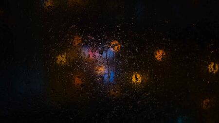 Close-up of raindrops on glass on background of blurred lights in dark. Concept. Blurred lights...