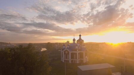 Russian Church in sunset rays of sun on background of town. Stock footage. Top view of beautiful colorful Church lit by setting sun in Russian town.の写真素材