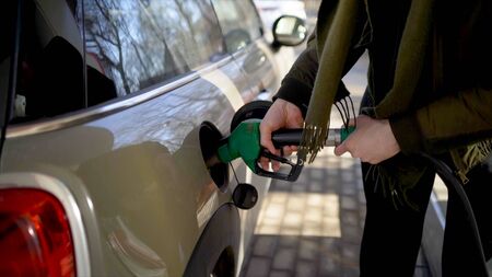 Man inserts hose into car at gas station. Action. Man nervously and quickly refuels car at gas...