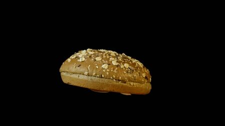 Close up of rotating burger bun in fire isolated on black background. Tasty fresh burger bun with...