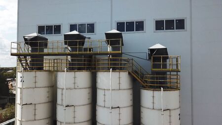 Aerial view of concrete mixing plant and four tanks. Stock footage. Flying over cement storage...