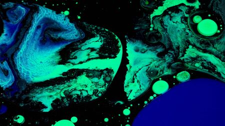 Close up of green and blue color oil paint being added into black inks. Stock footage. Mixed liquid...