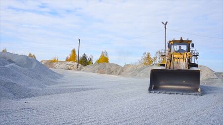 Tractor on construction site carries rubble. Stock footage. Tractor work on construction site or mining. Yellow tractor raking rubble from pileの写真素材