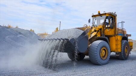 Tractor on construction site carries rubble. Stock footage. Tractor work on construction site or mining. Yellow tractor raking rubble from pileの写真素材
