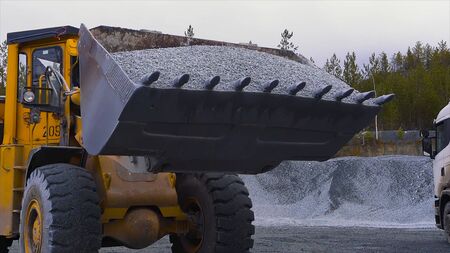 Tractor moves rubble to truck. Stock footage. Excavator-loader rakes rubble from pile at...