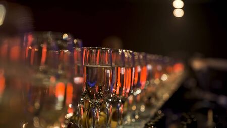 A lot of wine glasses with a cool delicious champagne or white wine at the bar. Alcohol background at the party, celebration concept.の写真素材