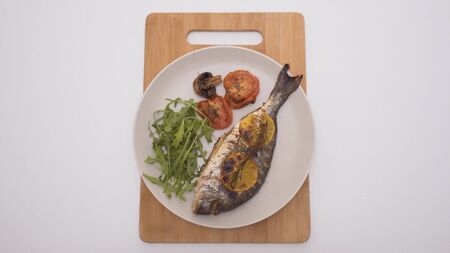 Baked fish with lemon and spices in restaurant. Action. Beautifully served fish in restaurant on...