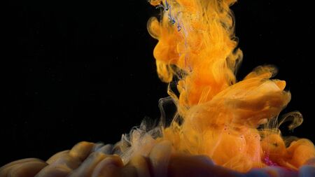 Close-up of flow of colored paints in water. Stock footage. Macro of beautiful splash of colored ink in water on black background.の写真素材