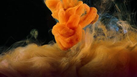 Close-up of flow of colored paints in water. Stock footage. Macro of beautiful splash of colored ink in water on black background.の写真素材