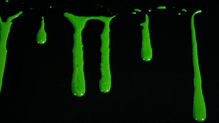 Drops and smudges of paint on glass. Stock footage. Bright acrylic paint drips on glass and runs down on black background. Paint flows on glass.の写真素材