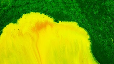 Mixing acidic paints. Stock footage. Bright acidic inks of different colors are mixed in stream on surface of liquid. Acidic thick paints create patterns with bubbles on surface.の写真素材