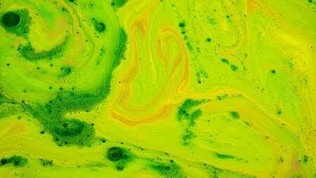 Mixing acidic paints. Stock footage. Bright acidic inks of different colors are mixed in stream on surface of liquid. Acidic thick paints create patterns with bubbles on surface.の写真素材