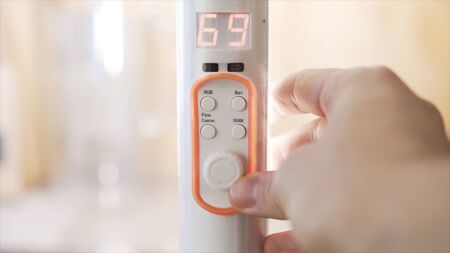 Close up of a hand turning remote controller of LED illumination in the room. Action. Color of light in the room is being changed from pink to purple with a remote controller.の写真素材