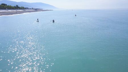 Couple floating on board with paddle. Clip. Top view of couple of vacationers during sea trip on SUP-Board. Seascape with couple engaged in sup-surfingの写真素材