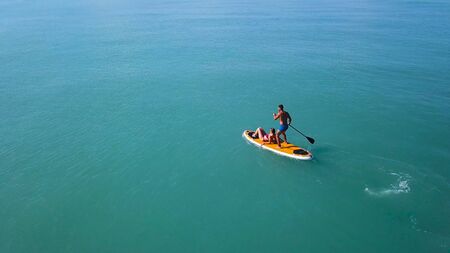 Couple floating on board with paddle. Clip. Top view of couple of vacationers during sea trip on SUP-Board. Seascape with couple engaged in sup-surfingの写真素材