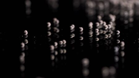 Close up of tiny gravel pile left on reflective black surface. Small stones at the laboratory during quality control of contruction materials process.の写真素材