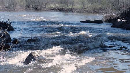 Fast flowing muddy river in spring. Clip. Strong flow of muddy mountain river during spring floods....