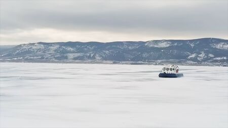 Hovercraft on the ice of lake Baikal in winter time. Clip. Aerial view of the air cushion vehicle on the thick ice of the frozen lake, sports transport and extreme concept.の写真素材