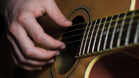 Close-up of man playing guitar. Concept. Professional guitar player moves fingers along strings of...
