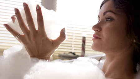 Young attractive brunette woman relaxing while taking a bubble bath. Video. Close up of female...