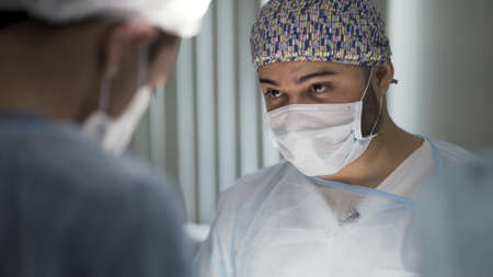 The medical surgeons team in the hospital performing surgical operation. Action. Men in clean...