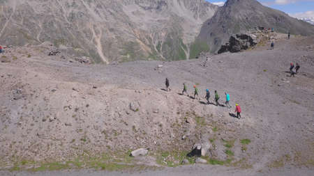 Top view of climbers walking to rocky mountain with snow peak. Clip. Active tourists went on...