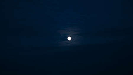 View of night sky with full moon and passing clouds. Concept. Wild nature with beautiful dark sky lit by moon. Cloudy night sky with full moonの写真素材