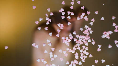 Close-up of sprinkle in shape of hearts. Concept. Bottom view of transparent glass with multicolored sprinkles scattered on it. Multi-colored sprinkles for decorationの写真素材