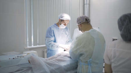 Team of doctors perform operation under anesthesia. Action. Operating room with surgeons and nurse...