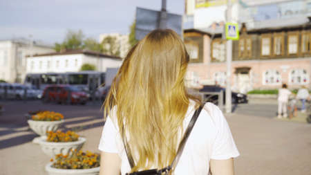 Back view of young woman with hair fluttering in wind. Media. Beautiful young woman with golden hair...