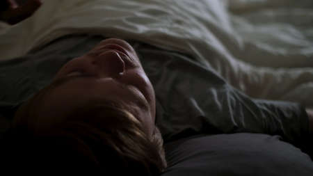 Close up of alarm clock on a digital cell phone display waking up a man in bed. Concept. Sleepy man...