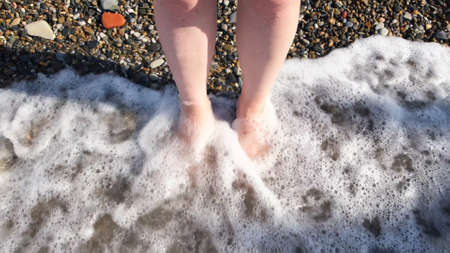 Top close up view of woman beautiful feet on a sea water and stones background. Concept. Concept of...
