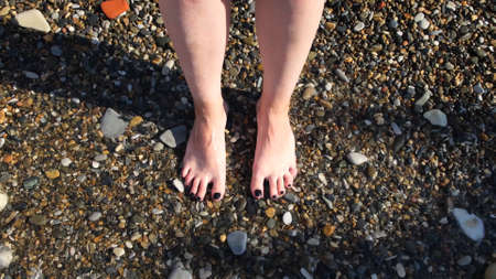 Top view of feet at the beach with sea waves. Concept. Connecting to nature, beautiful legs and feet...