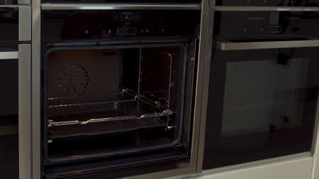 Close up of man unlocking and opening new modern mini oven for kitchen in furniture shop. Household...