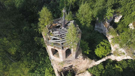 Aerial view of medieval church ruins in spring green forest. Clip. Concept of religion, top view of monastery ruins with green trees growing through.の写真素材