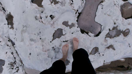 Man walking barefoot on giant stones in a clean mountain river. Clip. Travel concept, top view of...