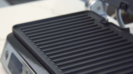 Close-up electric grill. Household utensils. Teflon surface on inside of new electric grill for...