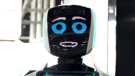 Funny robot with big blue eyes smiling and talking. Meida. Close up of robot face screen with friendly smile at the exhibition of modern technologies.の写真素材