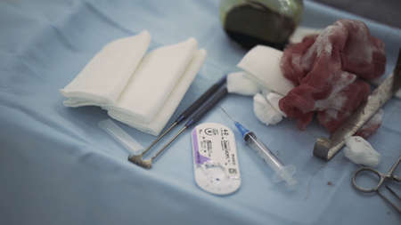 Bloody bandage on a medical table during surgery. Action. Close up of medical tools lying on a blue...