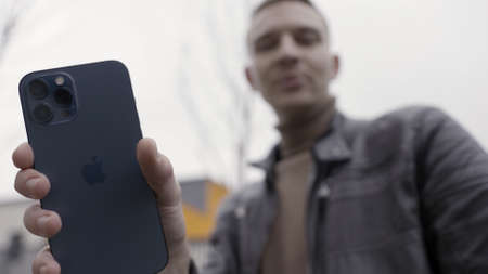 Saint Petersburg, Russia - 11.15.2020: Close up of a male hand holding new beautiful Iphone. Action. Demonstrating the new Apple Iphone 12 Pro max in pacific blue color.のeditorial素材