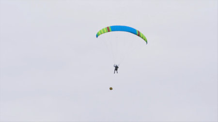 Bottom view of man with parachute in sky. Action. Person flies in sky on paraglider in cloudy weather. Extreme sports and skydivingの写真素材