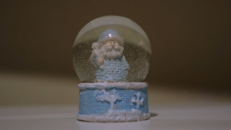 Christmas magic ball with Father Frost. Concept. Close up of a New Year symbol - glass ball with falling snow inside, souvenir standing on white table surface.の写真素材