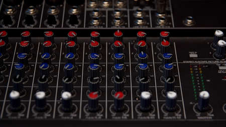 Sound producer hand is using a music mixer with editing tools. Media. Close up of male hand turning levers of a mixing console, concept of music production.の写真素材
