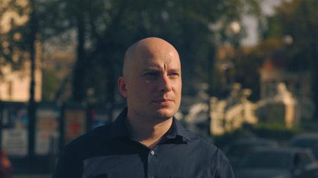 Close up of a hairless handsome male face with green eyes looking up on blurred street background. Stock footage. Bald caucasian man looking concentrated.の写真素材