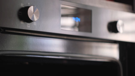 Close up of woman hand opening a modern cooking oven, kitchen utensils. Concept. Details of cooking process, putting a baking dish inside the oven.の写真素材