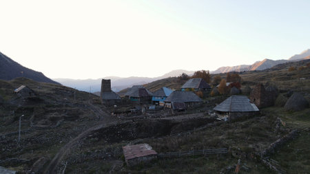 Aerial view of an old village with small houses in mountain valley. Action. Picturesque summer scenery of a calm village on cloudy sky background.の写真素材
