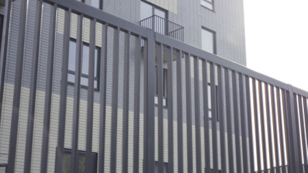 Apartment buildings with metal fence railing. Action. Close up of black iron fence with an apartment...