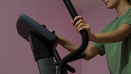 Beautiful athletic young girl on an elliptical trainer in the gym. Concept. Side view of a woman...